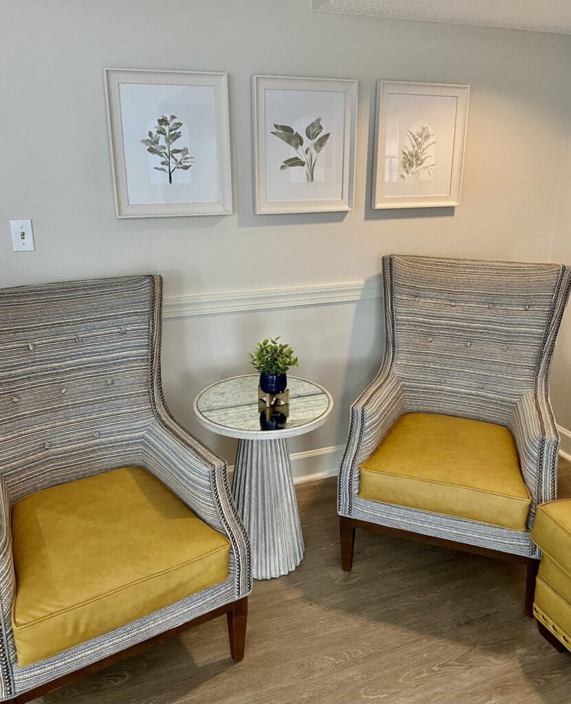 Two striped lounge chairs with yellow cushions and a small table in a welcoming Springwood Court common area.