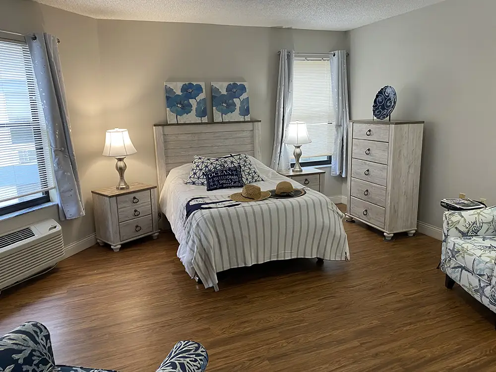 Bright, beach-themed senior living bedroom at Springwood Court in Florida with striped bedding and coastal decor.