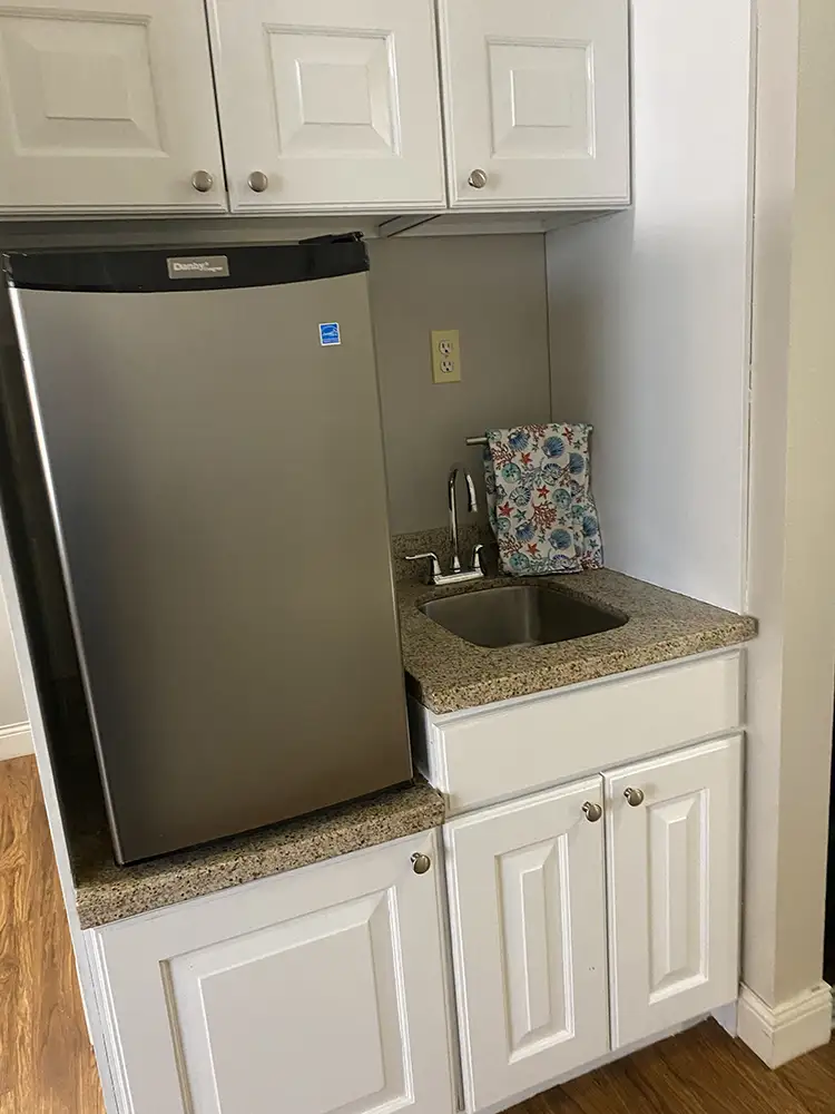 Compact kitchenette area in a senior apartment at Springwood Court, featuring a small fridge and sink.