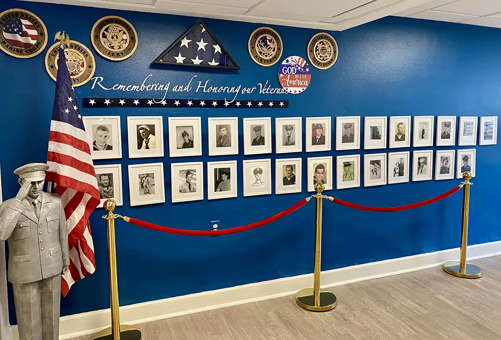 Veteran wall with framed military portraits and American flag, honoring residents at Springwood Court in Florida.